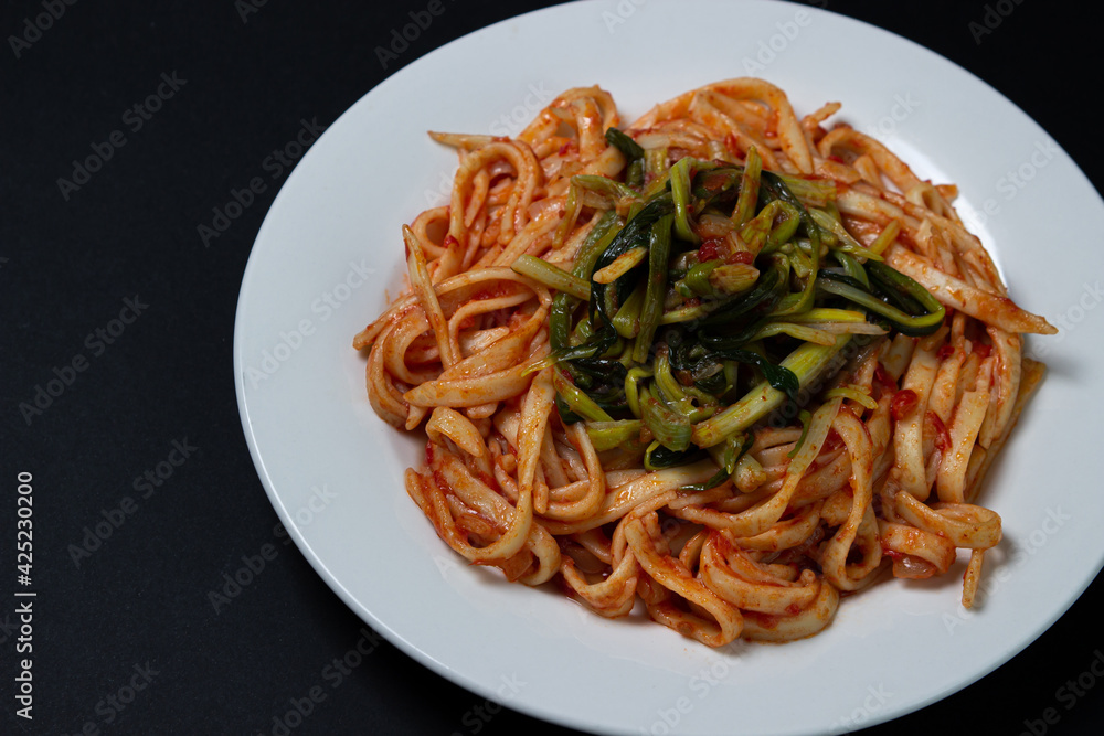 Spaghetti in tomato sauce on a dark background. Spaghetti with a vegetable side dish on a black background. Italian food. Tasty food