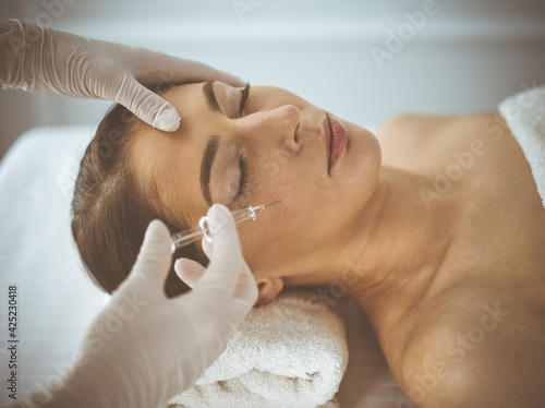 Beautician doing beauty procedure with syringe to face of young brunette woman. Cosmetic medicine and surgery, beauty injections © rogerphoto