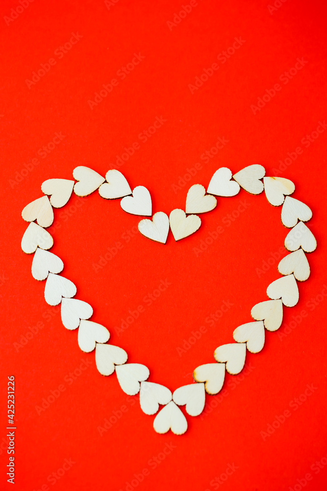Heart lined with wooden hearts on a bright red background. Place for an inscription, romantic picture for Valentine's Day