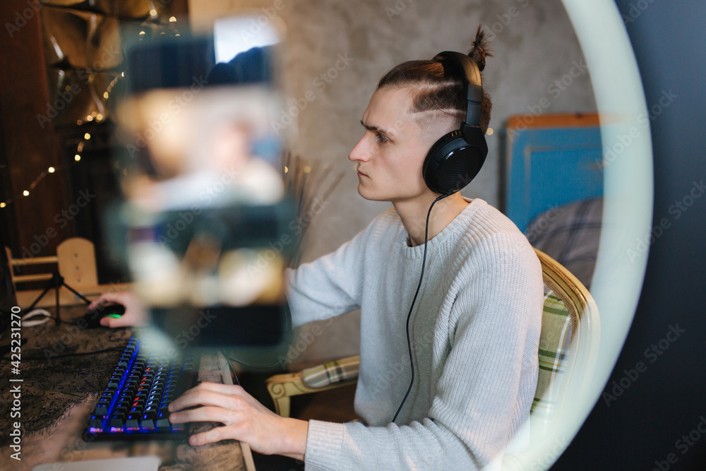 Man recording video on smartphone during the work at home on computer. Young guy recording on professional microphone speash about music Man recording video on smartphone during the work at home on computer. Young guy recording on professional microphone speash about music