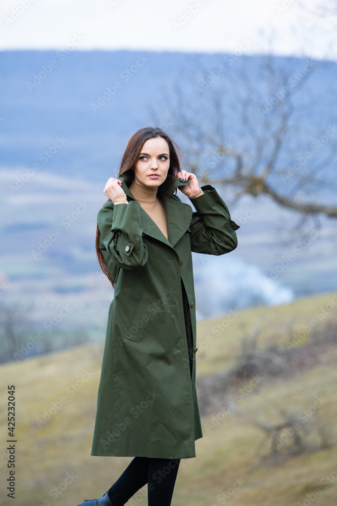Image of young beautiful woman wearing rain jacket in cold weather. Thinker european girl in spring nature. Image of young beautiful woman wearing rain jacket in cold weather. Thinker european girl in spring nature.