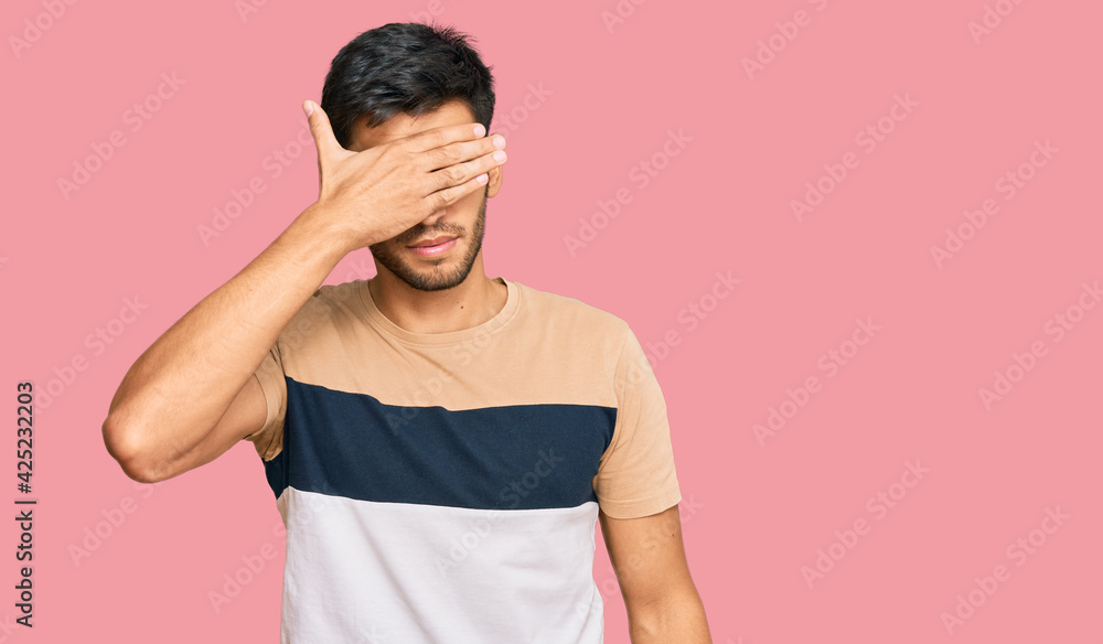 Young handsome man wearing casual clothes covering eyes with hand, looking serious and sad. sightless, hiding and rejection concept Young handsome man wearing casual clothes covering eyes with hand, looking serious and sad. sightless, hiding and rejection concept