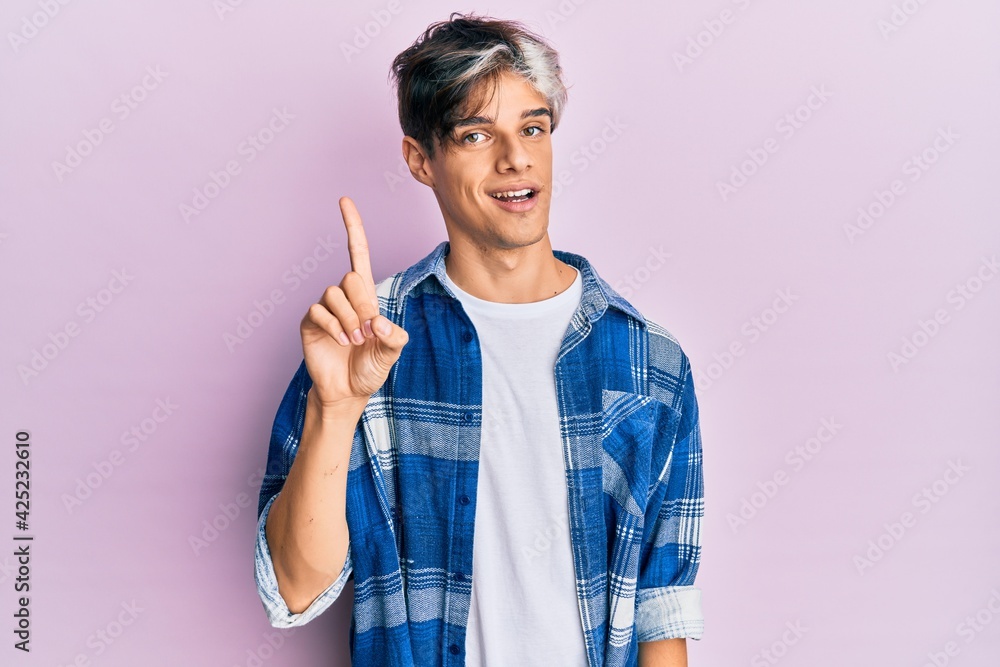 Young hispanic man wearing casual clothes showing and pointing up with finger number one while smiling confident and happy. Young hispanic man wearing casual clothes showing and pointing up with finger number one while smiling confident and happy.