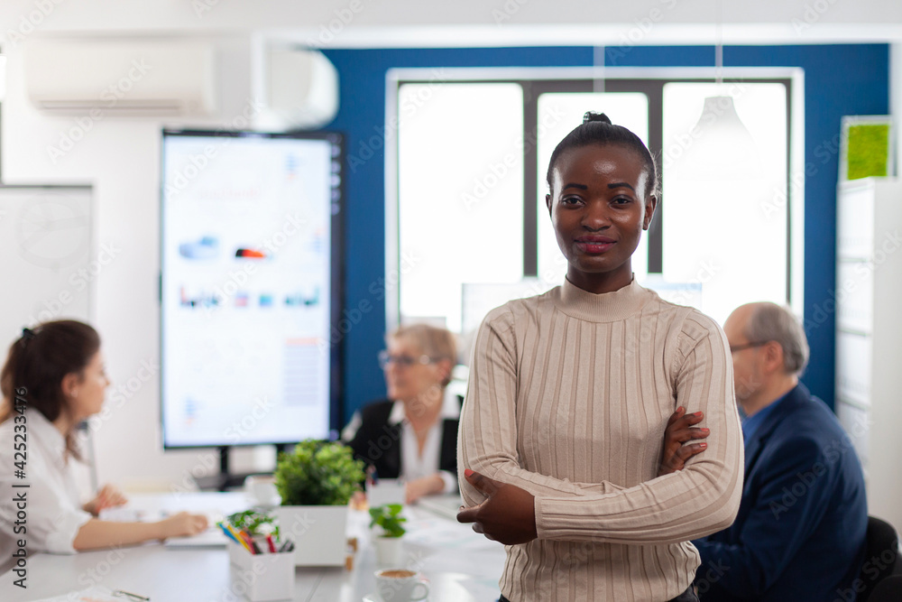 Successful smiling african business woman holding arms crossed looking atcamera in conference room. Manager working in professional start up financial business, modern company workplace ready for Successful smiling african business woman holding arms crossed looking atcamera in conference room. Manager working in professional start up financial business, modern company workplace ready for