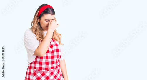 Young caucasian woman wearing apron tired rubbing nose and eyes feeling fatigue and headache. stress and frustration concept.