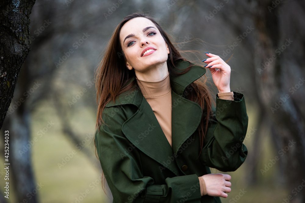 Image of young beautiful woman wearing rain jacket in cold weather. Thinker european girl in spring nature. Image of young beautiful woman wearing rain jacket in cold weather. Thinker european girl in spring nature.