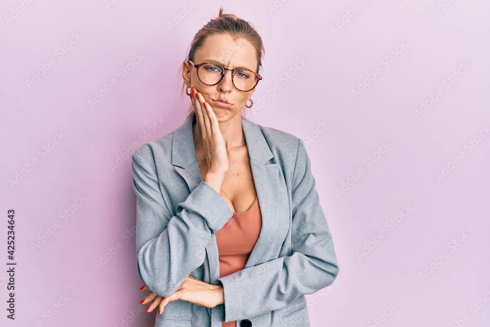 Beautiful caucasian woman wearing business jacket and glasses touching mouth with hand with painful expression because of toothache or dental illness on teeth. dentist
