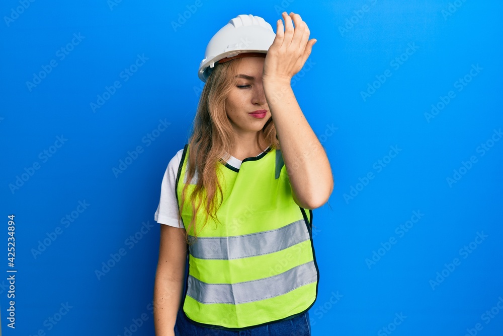 Beautiful blonde caucasian woman wearing architect hardhat surprised with hand on head for mistake, remember error. forgot, bad memory concept. Beautiful blonde caucasian woman wearing architect hardhat surprised with hand on head for mistake, remember error. forgot, bad memory concept.