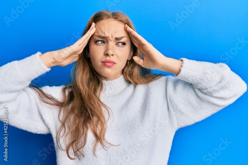 Beautiful blonde caucasian woman wearing casual winter sweater with hand on head, headache because stress. suffering migraine.