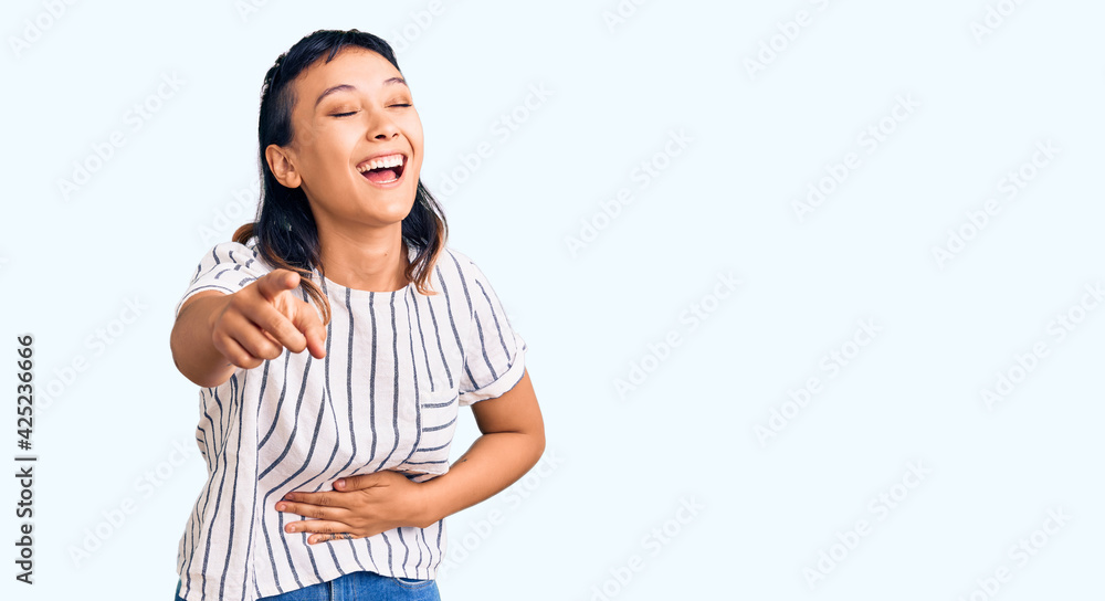 Young woman wearing casual clothes laughing at you, pointing finger to the camera with hand over body, shame expression Young woman wearing casual clothes laughing at you, pointing finger to the camera with hand over body, shame expression