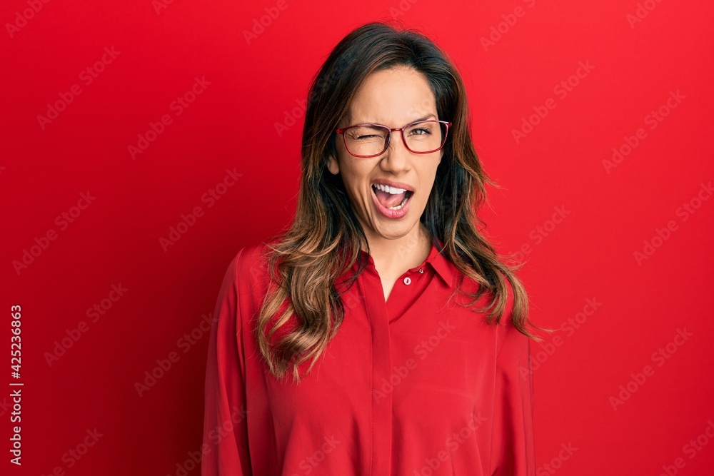 Young latin woman wearing casual clothes and glasses winking looking at the camera with sexy expression, cheerful and happy face. Young latin woman wearing casual clothes and glasses winking looking at the camera with sexy expression, cheerful and happy face.