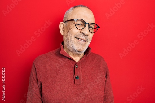 Handsome mature man wearing casual sweater and glasses with a happy and cool smile on face. lucky person. © Krakenimages.com