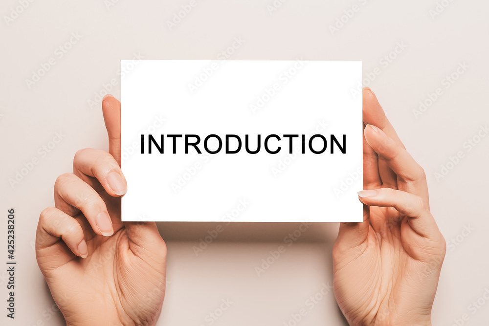 Female hands hold card paper with text Introduction on a yellow background. Business and finance concept Female hands hold card paper with text Introduction on a yellow background. Business and finance concept