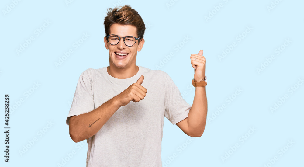 Handsome caucasian man wearing casual clothes and glasses pointing to the back behind with hand and thumbs up, smiling confident Handsome caucasian man wearing casual clothes and glasses pointing to the back behind with hand and thumbs up, smiling confident