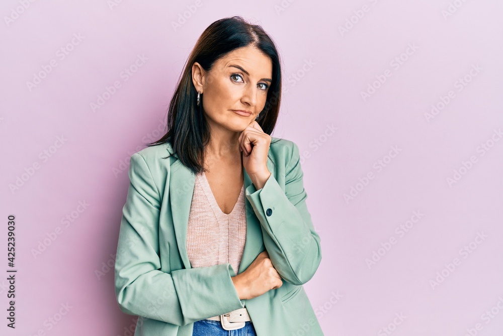 Middle age brunette woman wearing casual clothes with hand on chin thinking about question, pensive expression. smiling with thoughtful face. doubt concept. Middle age brunette woman wearing casual clothes with hand on chin thinking about question, pensive expression. smiling with thoughtful face. doubt concept.