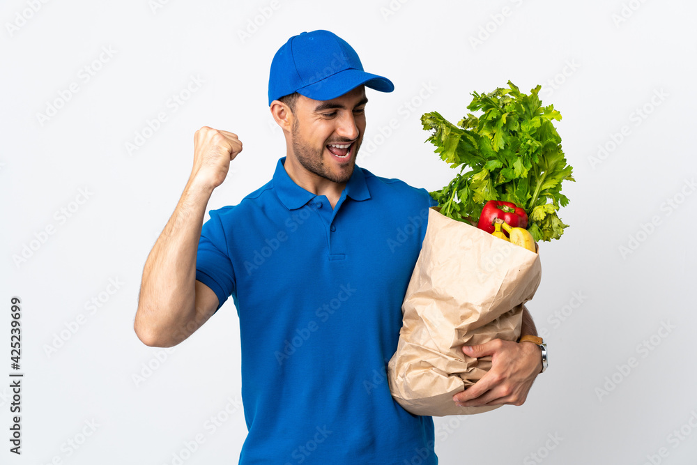 Delivery man with vegetables isolated on white background celebrating a victory Delivery man with vegetables isolated on white background celebrating a victory