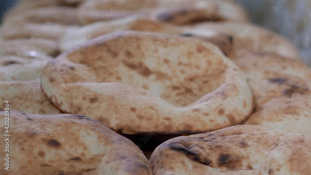 Traditional oriental flat bread from tandoori on the bakery shelf. A baker is putting another one pitta on top, close-up Traditional oriental flat bread from tandoori on the bakery shelf. A baker is putting another one pitta on top, close-up
