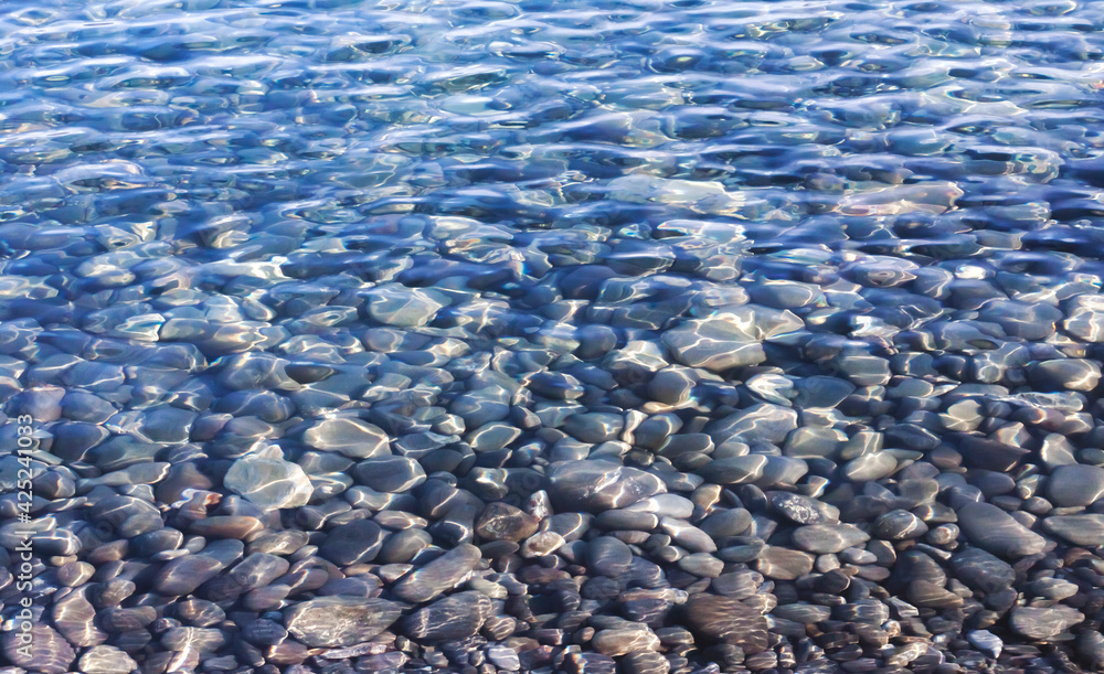 The gray pebble bottom shines through the clear rippled water