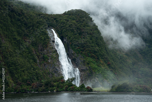 Lady Bowen Falls in Milford Sound with Southern Rata forest in bloom
