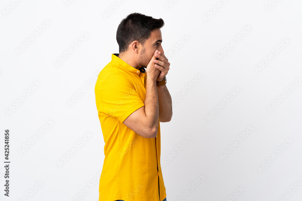 Young handsome man over isolated background covering mouth and looking to the side Young handsome man over isolated background covering mouth and looking to the side