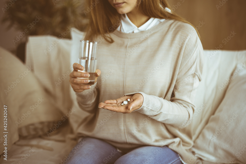 Fototapeta premium Close-up woman holding pills time to take medications, cure for headache, high blood pressure pain killer drugs at home. Stay at home concept during Coronavirus pandemic