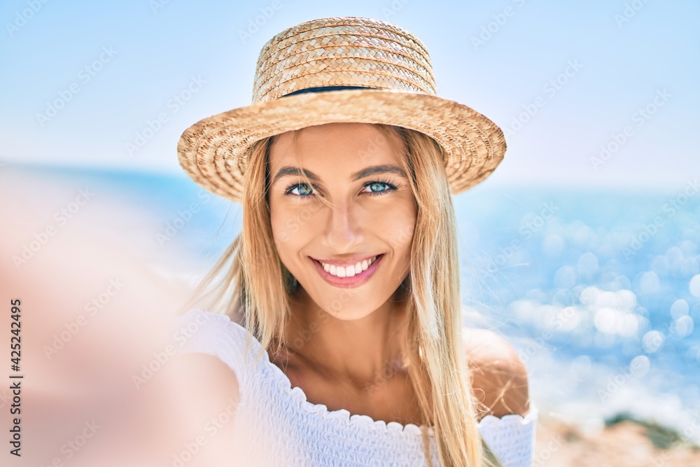 Young blonde tourist girl smiling happy making selfie by the camera at the promenade.