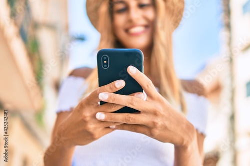 Young blonde tourist girl smiling happy using smartphone at the city.