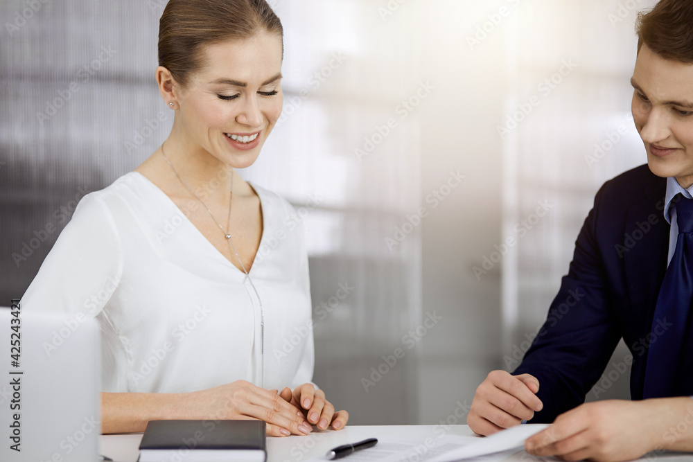 Business people discussing something while sitting in sunny office. Focus at businesswoman while talking to her male colleague Business people discussing something while sitting in sunny office. Focus at businesswoman while talking to her male colleague