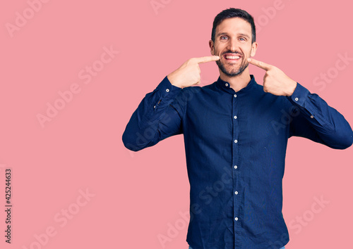 Young handsome man wearing casual shirt smiling cheerful showing and pointing with fingers teeth and mouth. dental health concept.