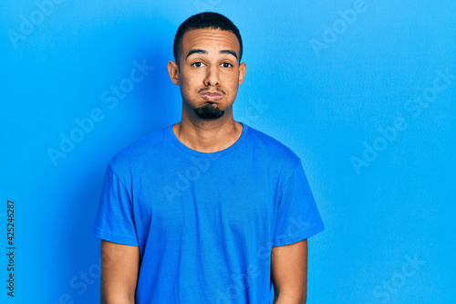 Young african american man wearing casual blue t shirt puffing cheeks with funny face. mouth inflated with air, crazy expression.