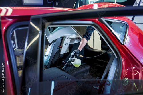 A car service worker cleans interiror with a special foam generator