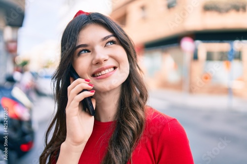 Young caucasian woman smiling happy talking on the smartphone walking at the city.