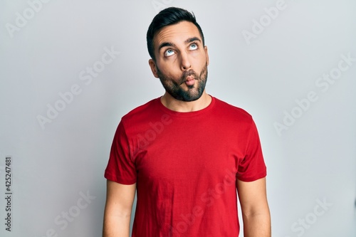 Young hispanic man wearing casual clothes making fish face with lips, crazy and comical gesture. funny expression.