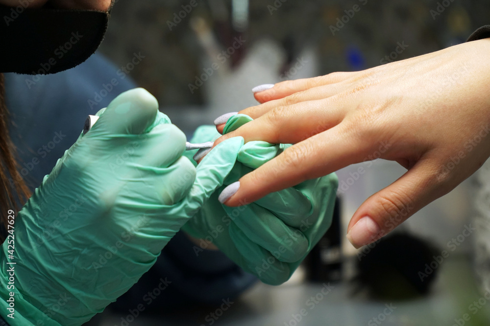 A manicure master does a manicure on the hand of a young woman A manicure master does a manicure on the hand of a young woman