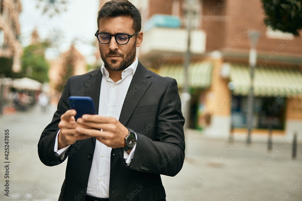 Young hispanic businessman with serious expression using smartphone at the city. Young hispanic businessman with serious expression using smartphone at the city.