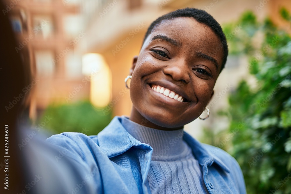Young african american woman smiling happy making selfie by the camera at the city. Young african american woman smiling happy making selfie by the camera at the city.