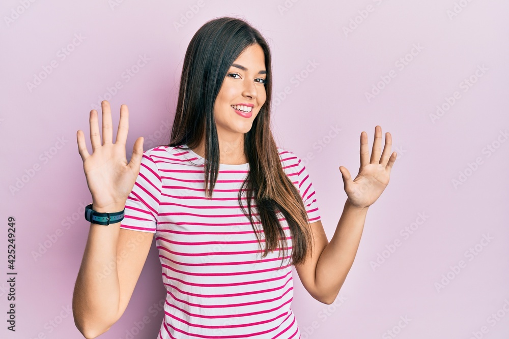 Young brunette woman wearing casual clothes over pink background showing and pointing up with fingers number ten while smiling confident and happy. Young brunette woman wearing casual clothes over pink background showing and pointing up with fingers number ten while smiling confident and happy.