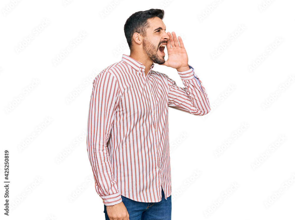 Young hispanic man wearing business shirt shouting and screaming loud to side with hand on mouth. communication concept. Young hispanic man wearing business shirt shouting and screaming loud to side with hand on mouth. communication concept.