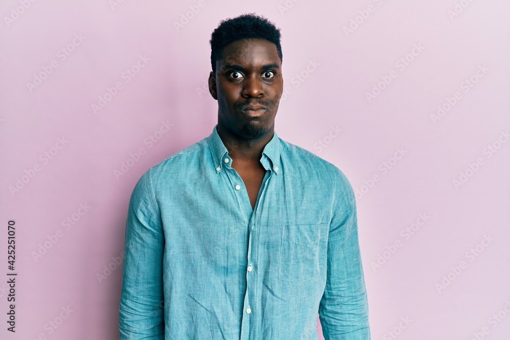 Handsome black man wearing casual clothes puffing cheeks with funny face. mouth inflated with air, crazy expression. Handsome black man wearing casual clothes puffing cheeks with funny face. mouth inflated with air, crazy expression.