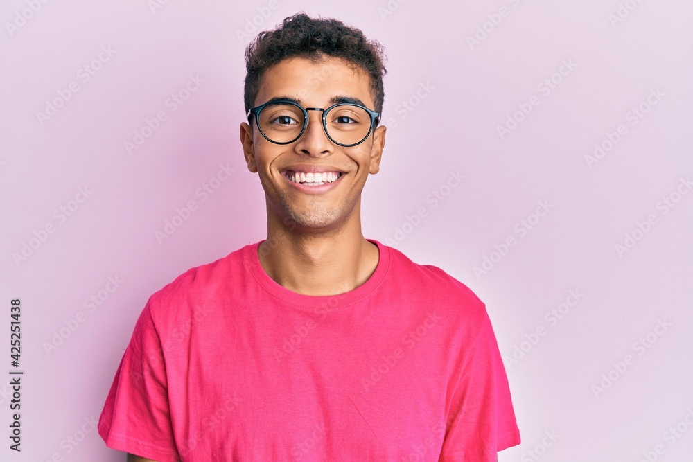 Young handsome african american man wearing glasses over pink background with a happy and cool smile on face. lucky person. Young handsome african american man wearing glasses over pink background with a happy and cool smile on face. lucky person.
