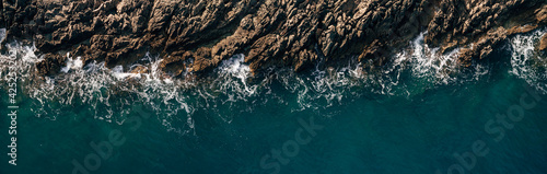 Aerial view of crashing waves on rocks, landscape overlooking nature and beautiful tropical sea overlooking the seaside in summer season.