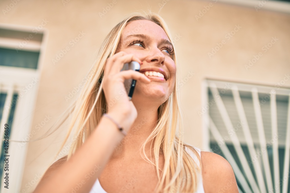 Young blonde girl smiling happy talking on the smartphone at the city. Young blonde girl smiling happy talking on the smartphone at the city.