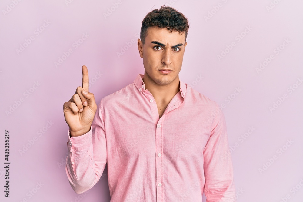 Hispanic young man pointing up with fingers skeptic and nervous, frowning upset because of problem. negative person. Hispanic young man pointing up with fingers skeptic and nervous, frowning upset because of problem. negative person.