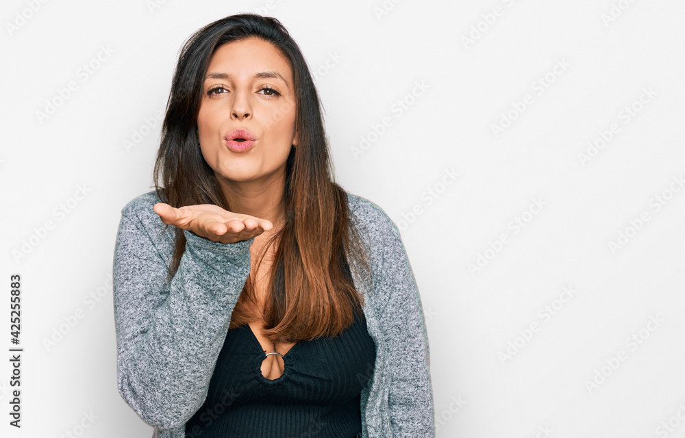 Beautiful hispanic woman wearing casual clothes looking at the camera blowing a kiss with hand on air being lovely and sexy. love expression. Beautiful hispanic woman wearing casual clothes looking at the camera blowing a kiss with hand on air being lovely and sexy. love expression.