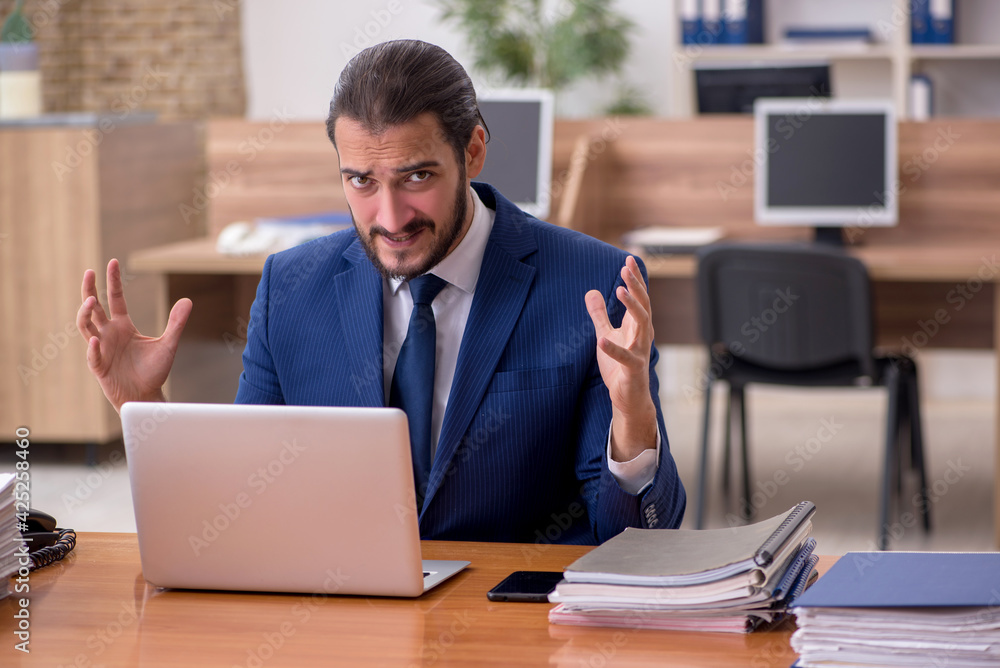 Young businessman employee unhappy with excessive work in the of Young businessman employee unhappy with excessive work in the of