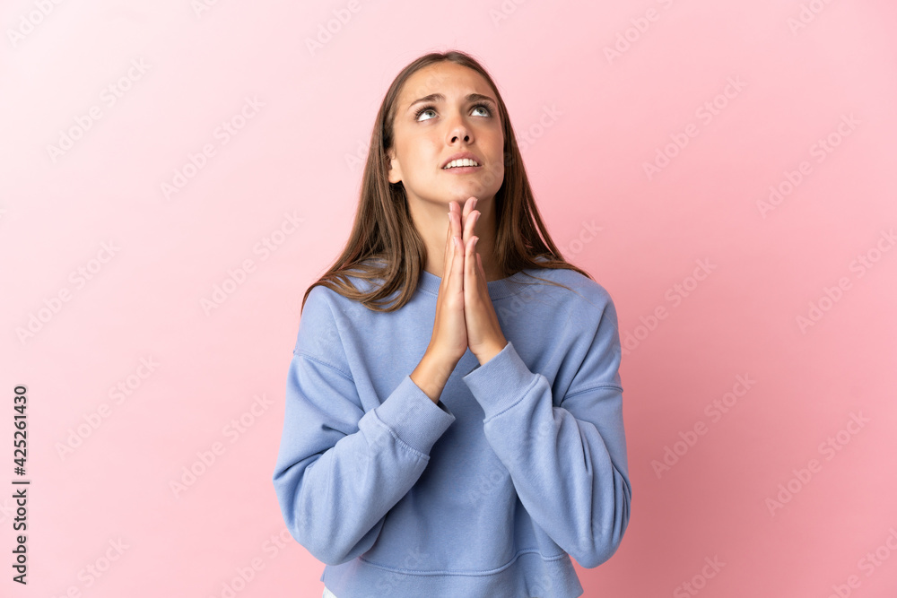 Young woman over isolated pink background keeps palm together. Person asks for something Young woman over isolated pink background keeps palm together. Person asks for something