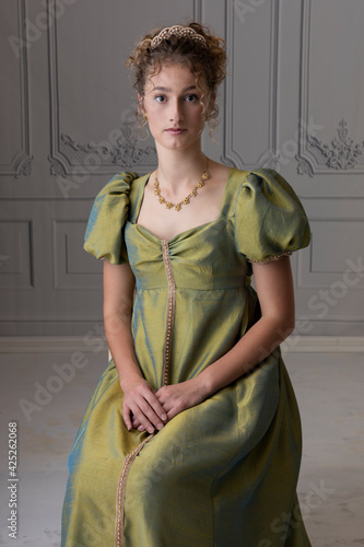 Принти на полотні A young Regency woman wearing a green silk shot dress and tiara and sitting in a