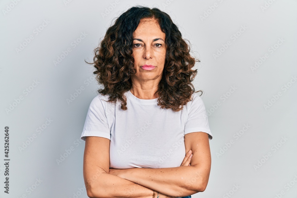 Middle age hispanic woman with arms crossed gesture relaxed with serious expression on face. simple and natural looking at the camera. Middle age hispanic woman with arms crossed gesture relaxed with serious expression on face. simple and natural looking at the camera.