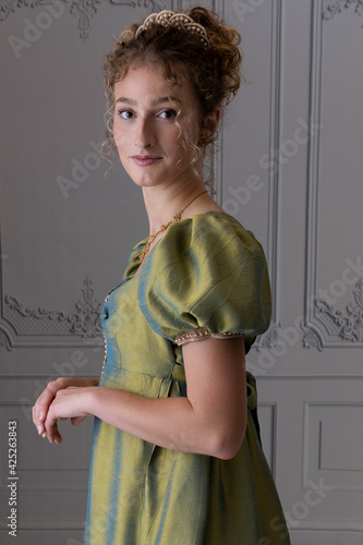 Foto A young Regency woman wearing a green shot silk dress standing against a paneled