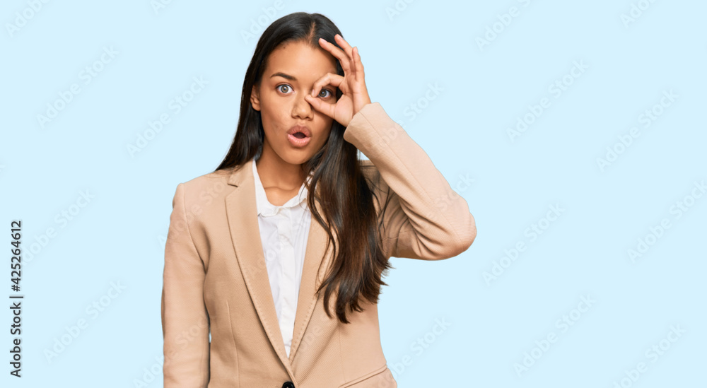Beautiful hispanic woman wearing business jacket doing ok gesture shocked with surprised face, eye looking through fingers. unbelieving expression. Beautiful hispanic woman wearing business jacket doing ok gesture shocked with surprised face, eye looking through fingers. unbelieving expression.